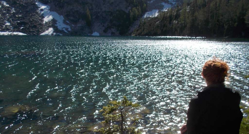 a person sits at the edge of a body of water on an outward bound course